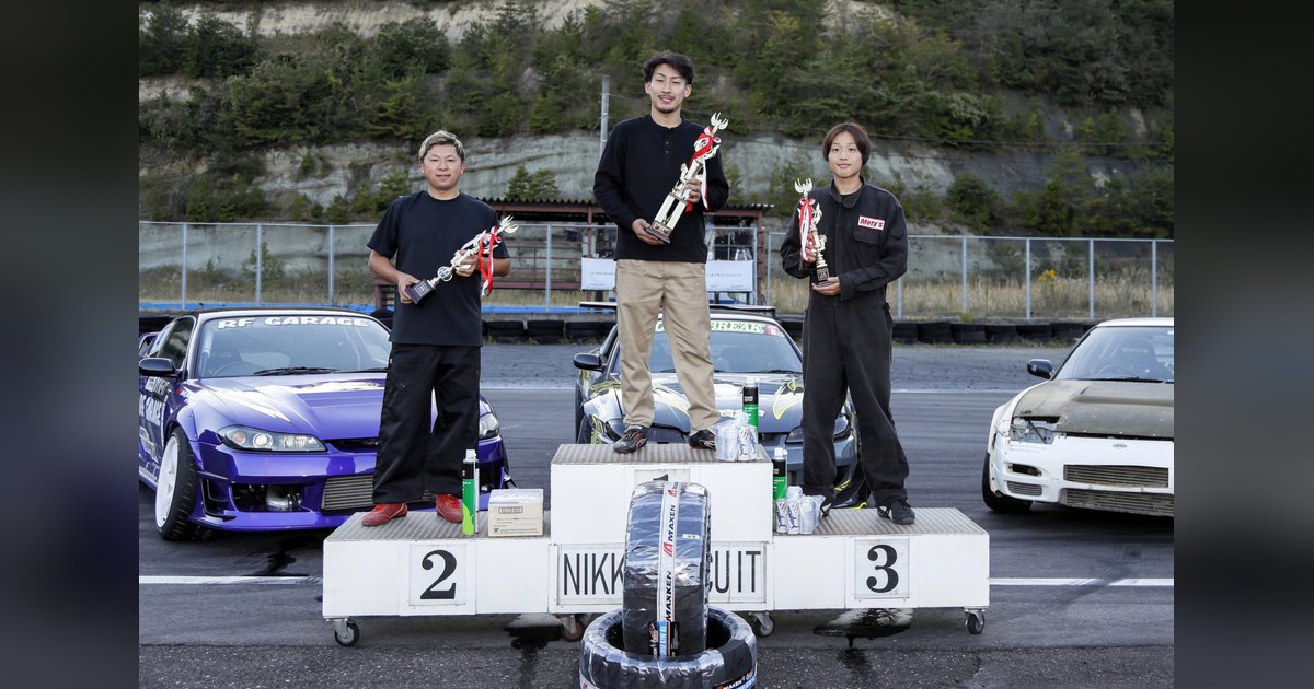 Tsuyoshi Nakagawa holds the winner's trophy on the top step of the Nikko Circuit podium, flanked by the second and third placed drivers, at D1 NEXT Central Series 2026 Rd.4