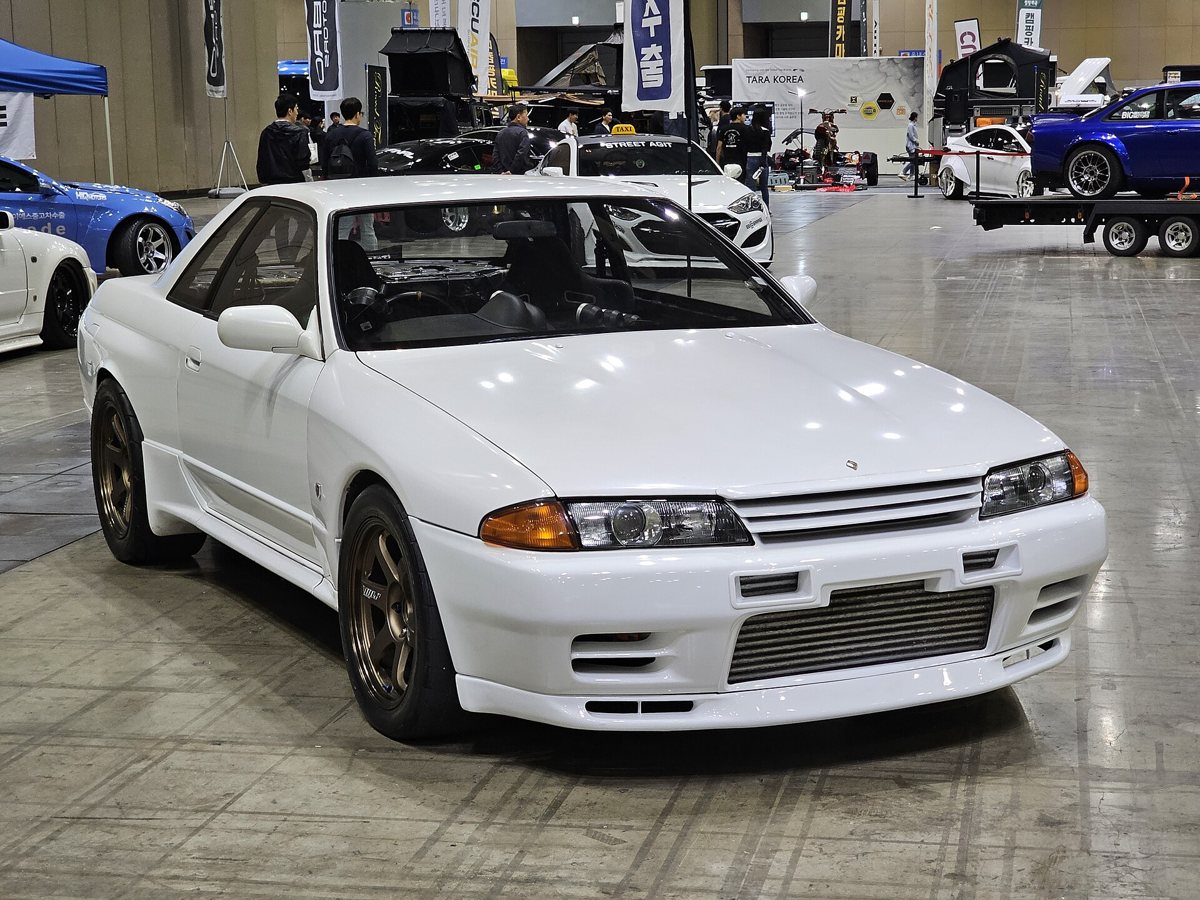 A white Nissan Skyline R32 GT-R at an indoor car show