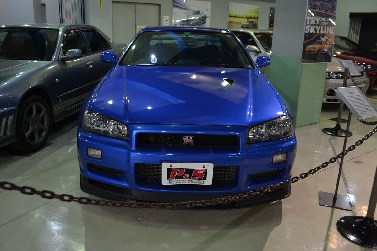 A blue Nissan Skyline GT-R R34 V-spec II on display at a museum in Japan