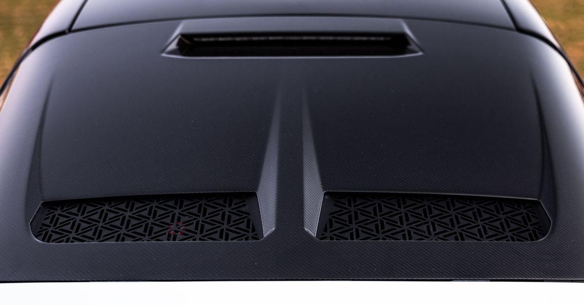 Close-up of a black carbon-fibre bonnet with a central scoop and two meshed vents