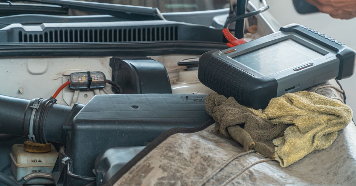 A generic handheld diagnostic tool resting on an open engine bay (stock photo, not a Power FC or FC Commander)