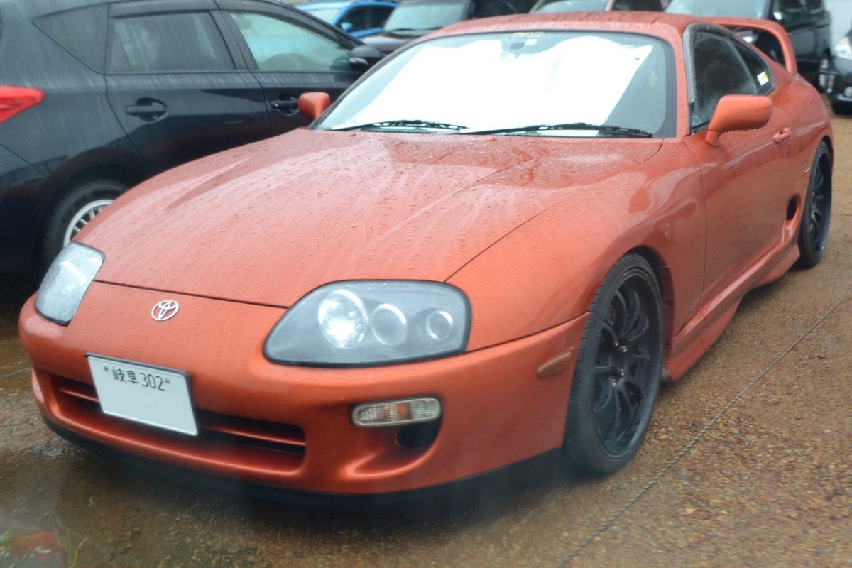 An orange Toyota JZA80 Supra RZ on Japanese plates, the model where buying in Japan still beats US auction prices
