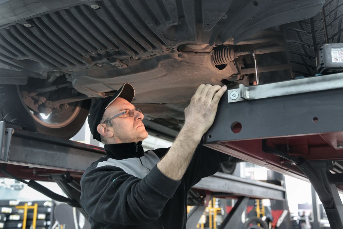 A mechanic inspecting the underside of a car on a lift