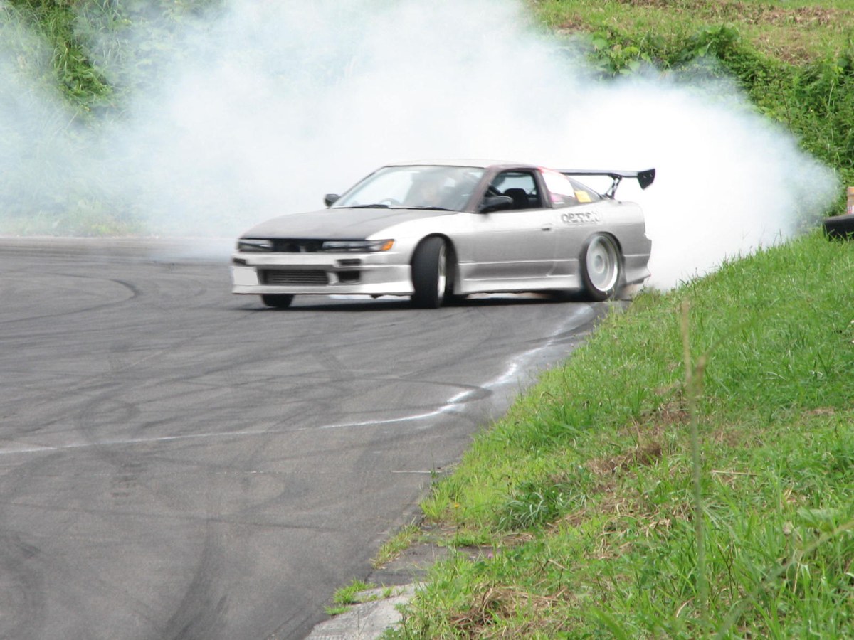 A silver Sileighty — 180SX body with a Silvia front end — mid-drift on a Japanese course