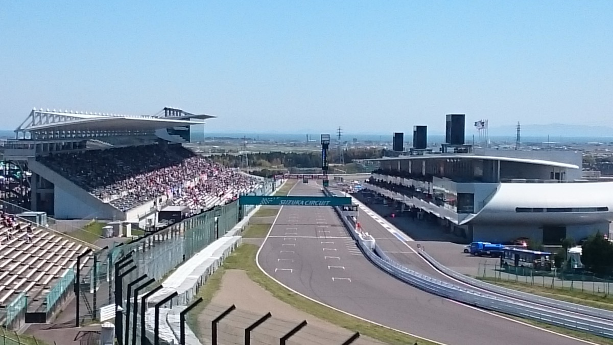 The main straight and grandstands at Suzuka Circuit, empty, with the SUZUKA CIRCUIT gantry over the track