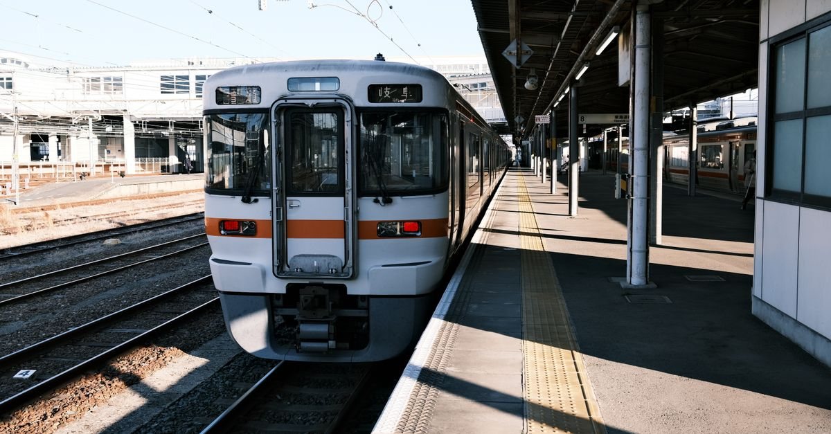 A JR Central local train, white with an orange stripe, waiting at a station platform with the destination Gifu on its display